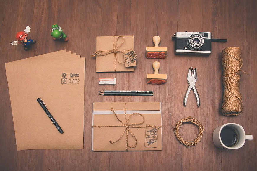 Flat lay of craft supplies, vintage camera, and coffee on wood