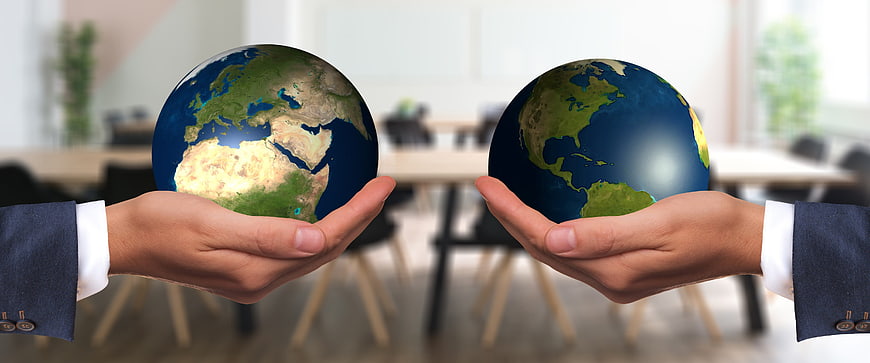 Two hands holding globes in business office background