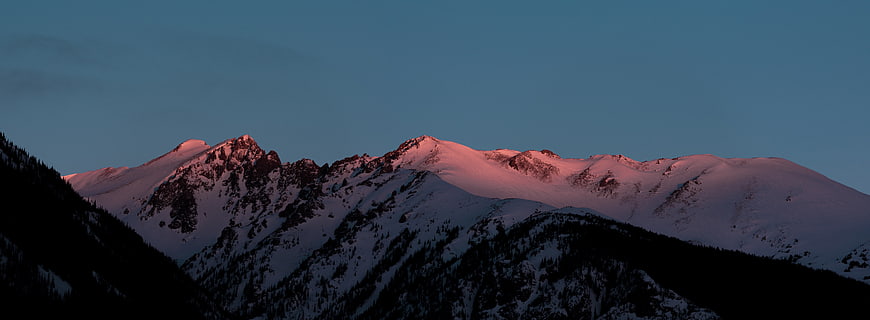 Snow-Capped Mountain Peaks Bathed in Pink Alpenglow at Dusk
