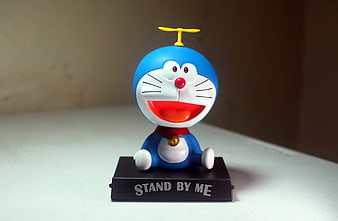 Doraemon toy figure sitting on a black stand with text