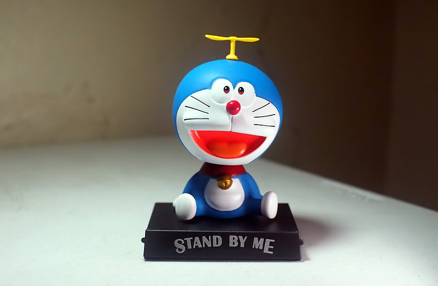 Doraemon toy figure sitting on a black stand with text