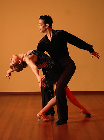 Couple performing dramatic ballroom dance lift in studio