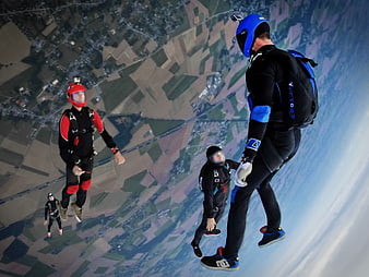 Skydivers in Freefall Over Patchwork Fields