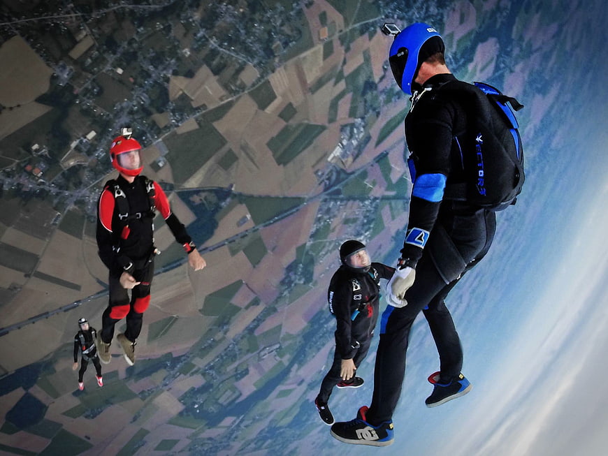Skydivers in Freefall Over Patchwork Fields