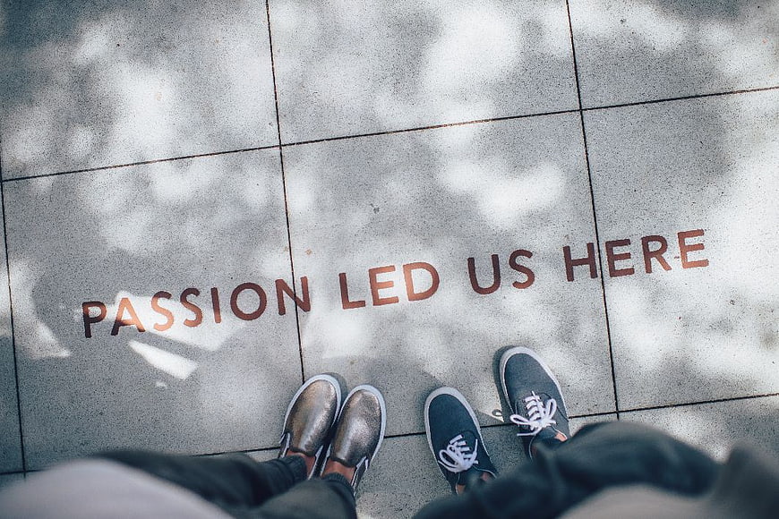 Couple standing on pavement with passion led us here text
