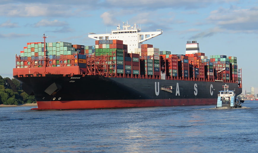 Large UASC Container Ship Navigating Waterway with Tugboat