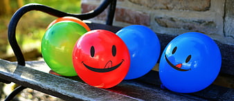 Colorful smiley face balloons on a wooden bench
