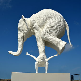 White Elephant Sculpture Crushing Human Figure Against Blue Sky
