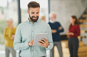 Smiling bearded man using tablet in modern office