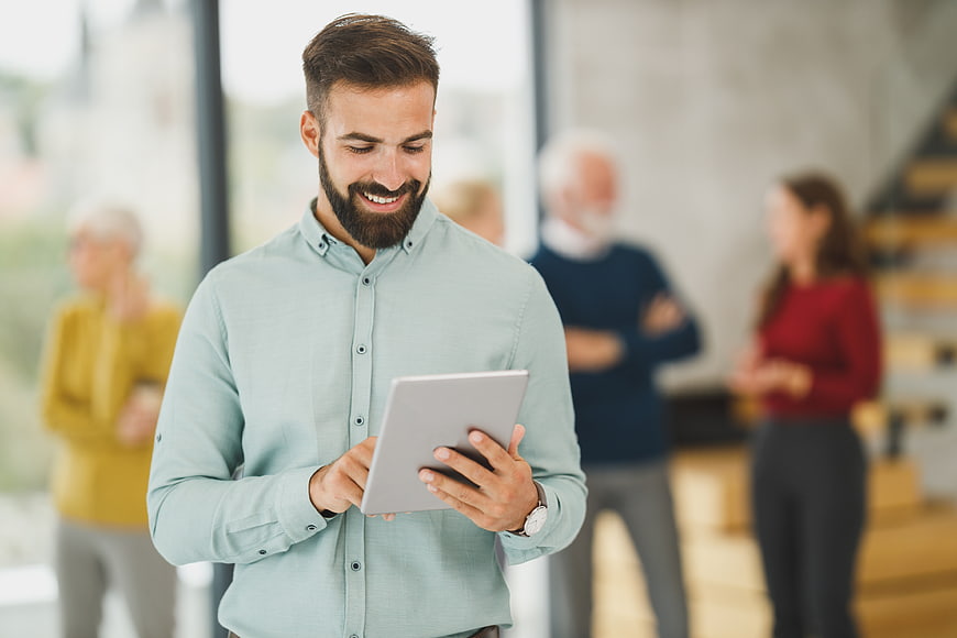 Smiling bearded man using tablet in modern office