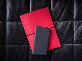 Red Notebook and Black Smartphone on Black Leather
