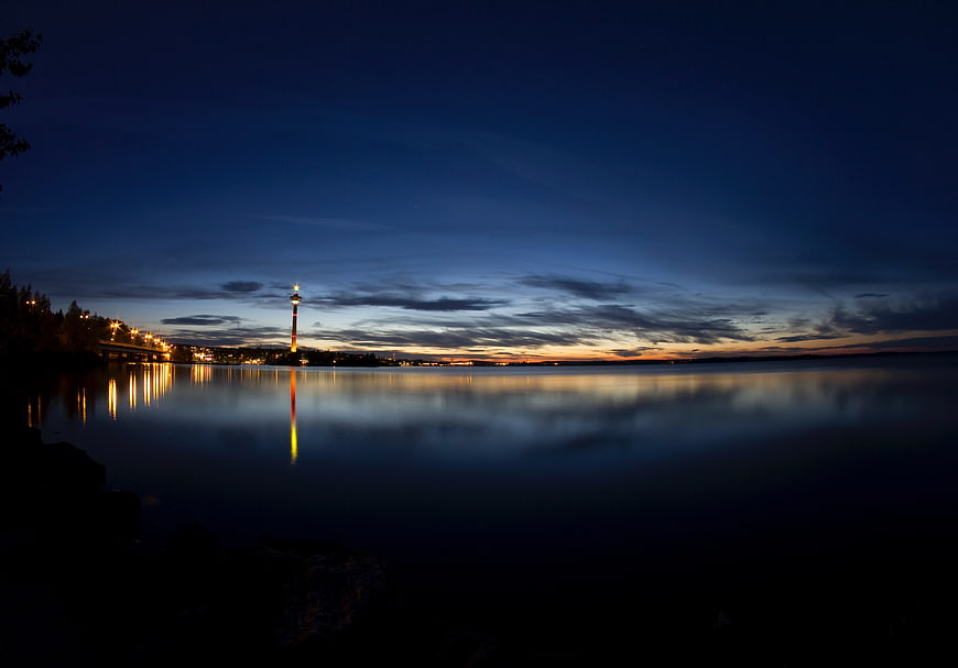 Serene Night Skyline with Tower Reflection on Calm Water