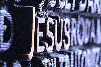Close-up of the word Jesus in metallic lettering on a dark textured background