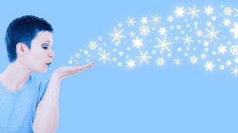 Woman blowing snowflakes against blue background