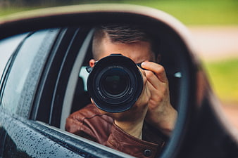 Photographer taking photo in car side mirror reflection