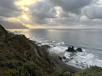 Dramatic Coastal Landscape with Sunlight Breaking Through Clouds