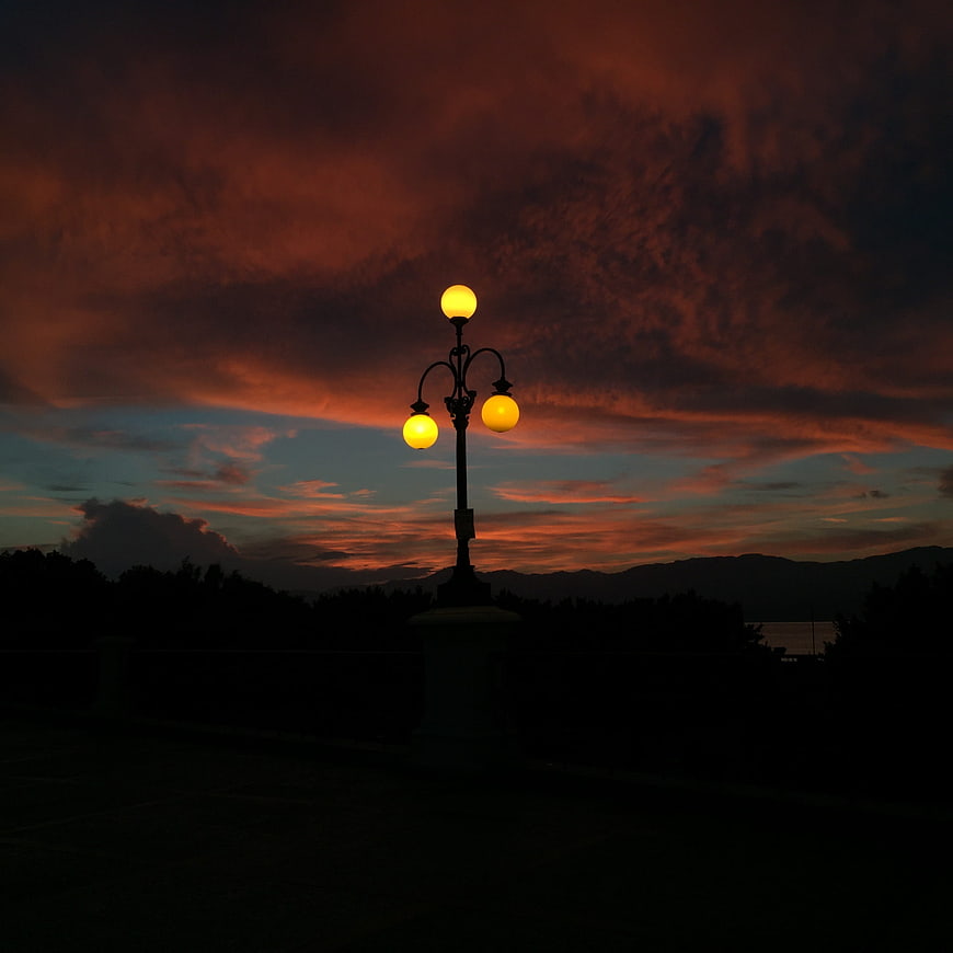 Glowing lamppost against dramatic red sunset sky