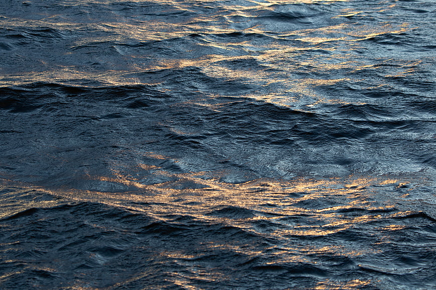 Golden Sunlight Reflecting on Dark Rippled Ocean Waves