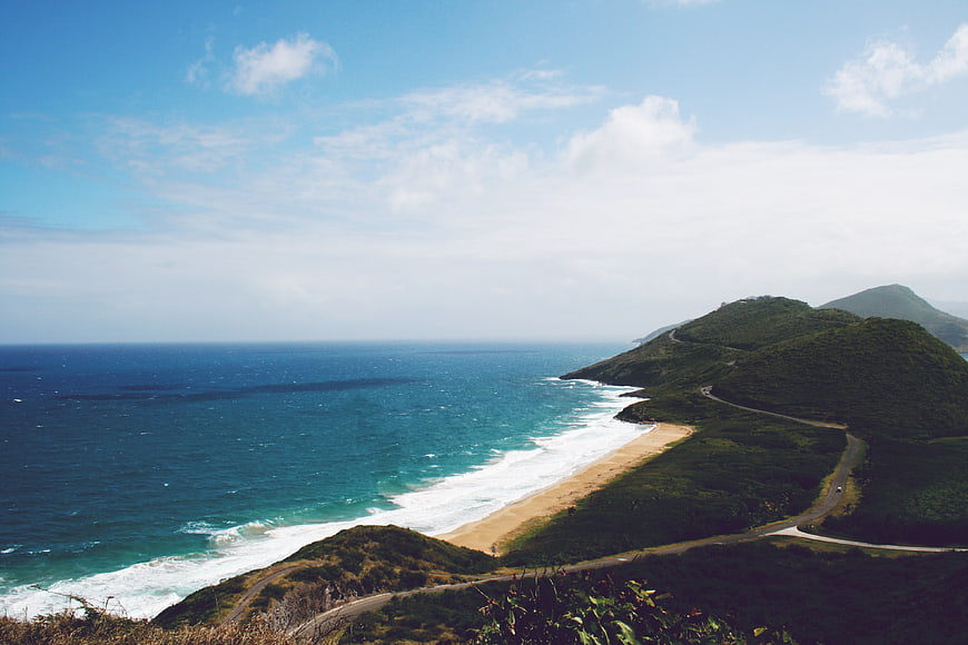 Scenic coastal road winding along green hills and turquoise ocean