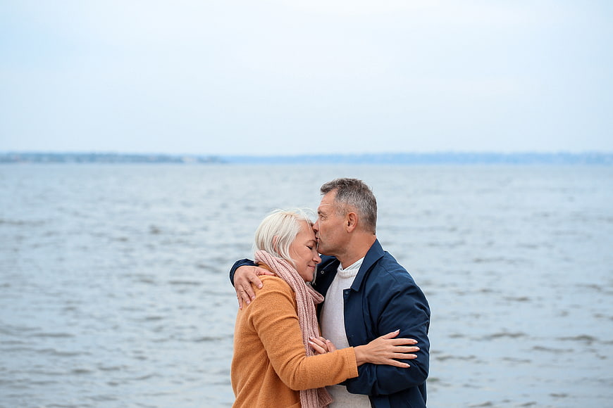Senior couple embracing and kissing by the sea