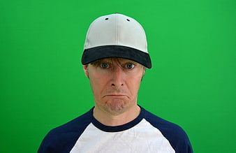Man in Baseball Cap Looking Skeptical on Green Screen