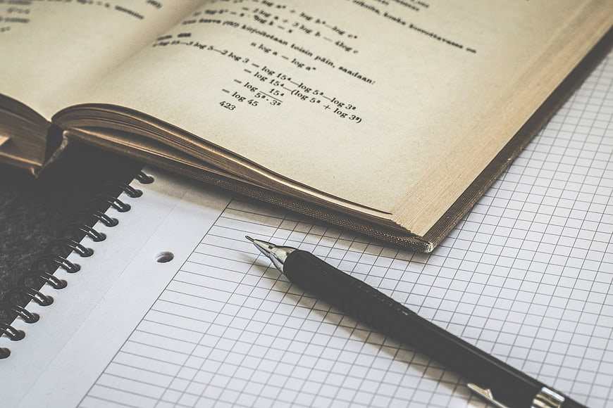 Open Math Textbook and Pen on Graph Paper