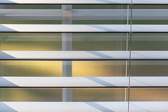 Close-up of white window blinds with sunlight and shadows