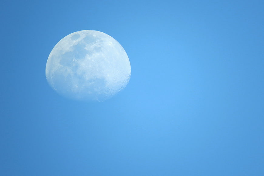 Full moon in clear blue daytime sky