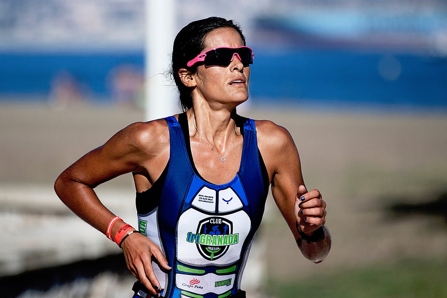 Female Triathlete Running on Beach in Blue Suit