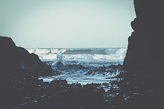 Ocean waves crashing through rocky cave opening