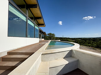 Modern House Infinity Pool with Wooden Deck and Blue Sky