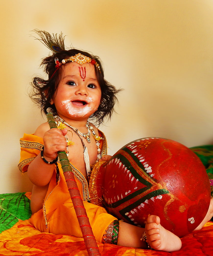 Baby dressed as Lord Krishna with peacock feather and butter pot