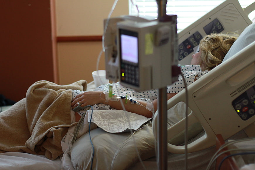Woman in hospital bed with IV drip and medical monitor during labor