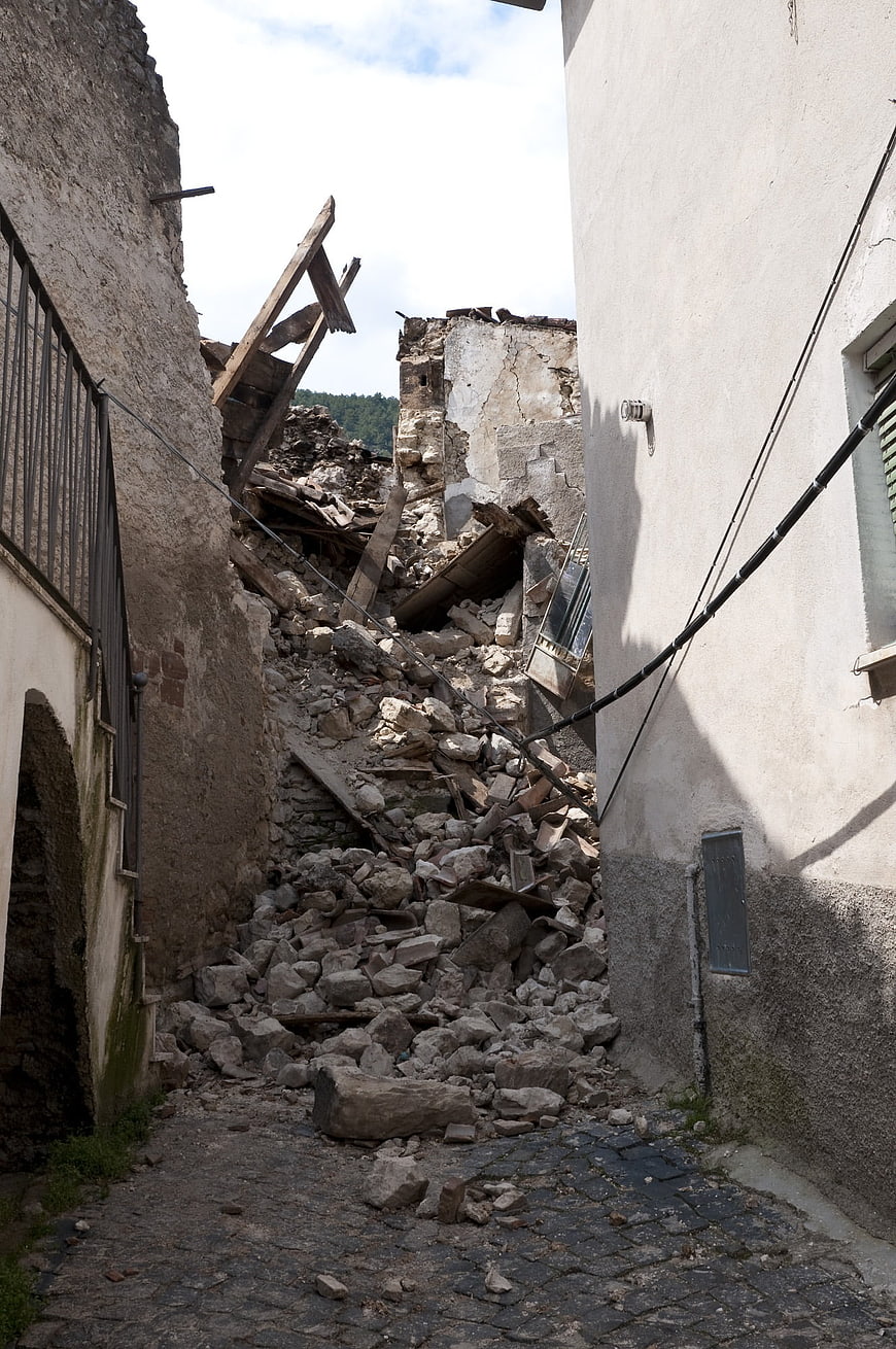 Collapsed stone building rubble in narrow alleyway