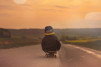 Child Skateboarding Down Country Road at Sunset