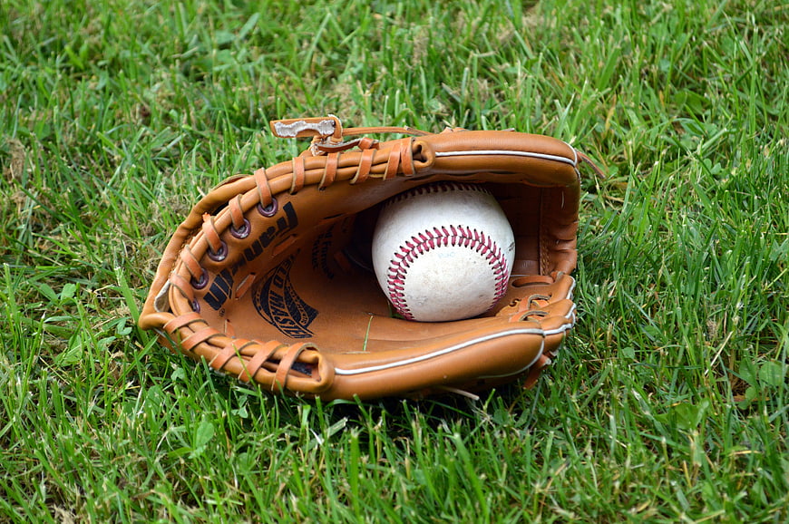 Baseball glove with ball on green grass field