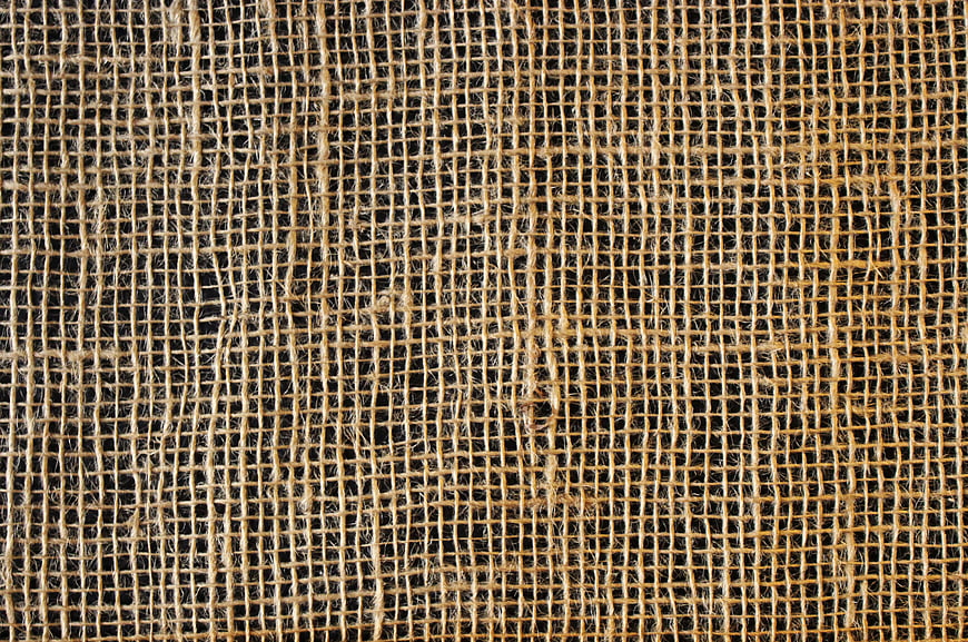 Close-up texture of woven burlap fabric on black background