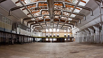 Abandoned industrial hall with ventilation pipes and brick floor