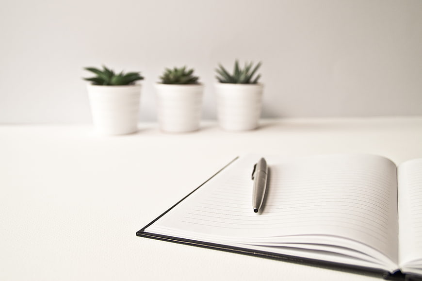Minimalist white desk with open notebook and pen