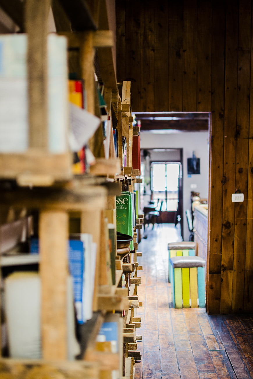 Rustic wooden bookshelf hallway with colorful stools