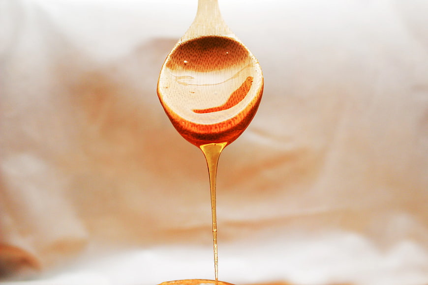 Golden Honey Dripping from Wooden Spoon
