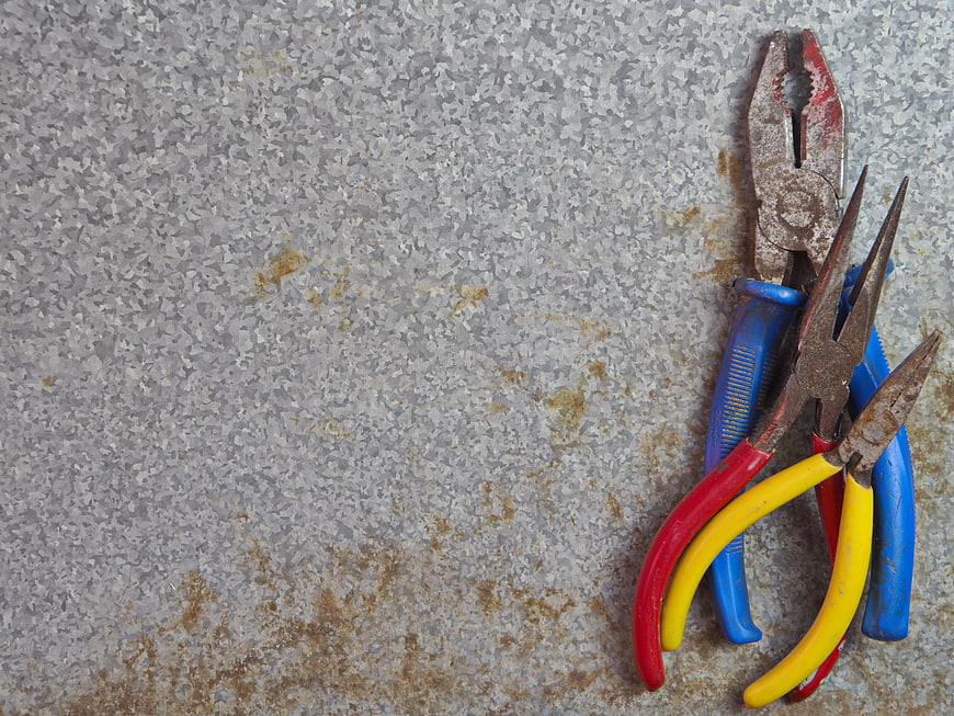 Rusty pliers on textured metal background with copyspace