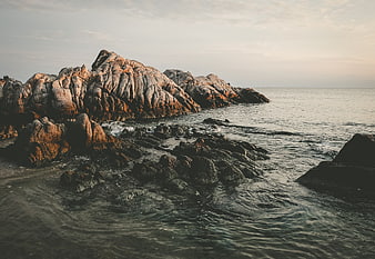 Rugged Coastal Rocks at Sunset with Calm Ocean Waves