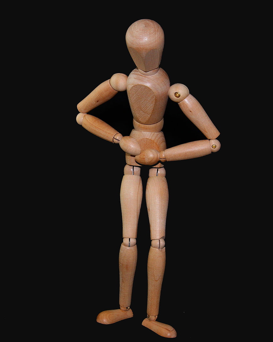 Wooden artist mannequin standing with hands on hips