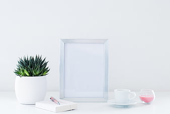 Minimalist white desk setup with succulent, notebook, and silver frame mockup