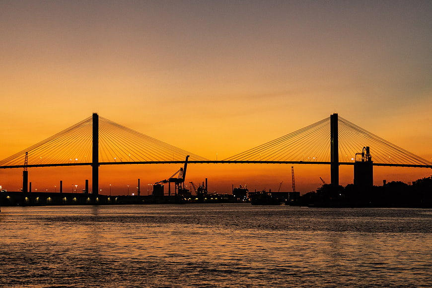 Silhouette of cable-stayed bridge at sunset over water