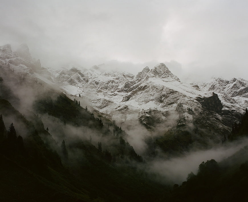 Misty Snow-Capped Mountain Peaks with Foggy Forest Slopes