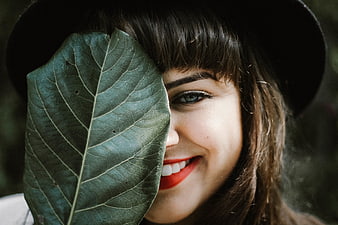 Smiling woman with leaf covering half her face