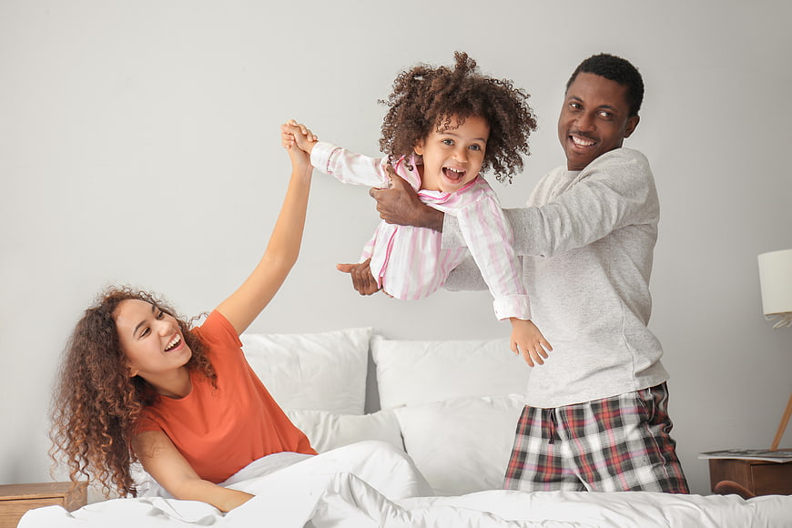 Happy African American Family Playing in Bed