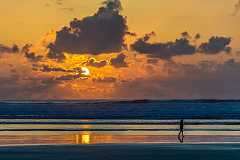 Silhouette of Woman Walking on Beach at Sunset